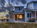 A welcoming two-story condo boasts a covered porch, an orange front door, and well-kept landscaping at 500 Lashley St # 58, Longmont, CO 80504