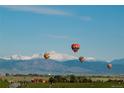 Scenic view of the community with hot air balloons, distant mountains, and green fields at 595 Twilight St, Erie, CO 80516