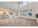 Spacious living room with tall windows, light wood flooring, and an open concept design at 595 Twilight St, Erie, CO 80516