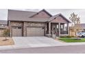 Beautiful stone exterior with a three-car garage and well-manicured lawn at 15804 Elizabeth Cir, Brighton, CO 80602
