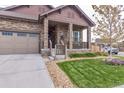 Inviting stone front porch with craftsman columns and fresh landscaping at 15804 Elizabeth Cir, Brighton, CO 80602