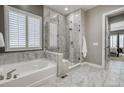 Elegant bathroom featuring a soaking tub, a glass-enclosed shower, and marble tile flooring at 15804 Elizabeth E Cir, Thornton, CO 80602