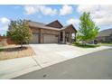 Charming home showcasing a three-car garage and inviting front yard, complemented by a lush tree and stone accents at 15804 Elizabeth E Cir, Thornton, CO 80602