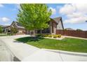 Well-maintained front lawn with mature trees and landscaped bushes, complete with a cozy porch and fenced yard at 15804 Elizabeth E Cir, Thornton, CO 80602