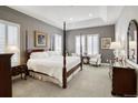 Inviting main bedroom with a four-poster bed, tray ceiling, and plantation shutters at 15804 Elizabeth E Cir, Thornton, CO 80602