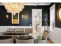 Elegant dining room with a glass table, stylish chandelier, and dark accent wall at 2475 S Adams St, Denver, CO 80210