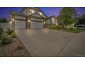 Charming two-story home at twilight with a three-car garage, stone accents, and well-manicured front yard at 5286 Rustic Ave, Firestone, CO 80504