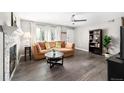 Bright living room featuring a decorative fireplace, plush sofa, and modern ceiling fan at 1391 Elmira St, Aurora, CO 80010