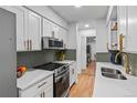 Contemporary kitchen with white cabinets, stainless steel appliances, and green tile backsplash at 7615 E Quincy Ave # 103, Denver, CO 80237