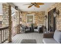 Cozy covered porch with stone walls, featuring stylish wicker seating, an overhead fan, and decorative lighting at 7836 S Fairfax Ct, Centennial, CO 80122