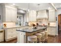An open kitchen boasts custom cabinets, pendant lighting, and a center island with stool seating at 7836 S Fairfax Ct, Centennial, CO 80122