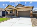 Inviting home exterior featuring a well-maintained lawn, covered porch, and a convenient two-car garage at 845 Leeward St, Lochbuie, CO 80603