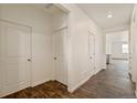 Bright hallway with wood-look floors, white walls, and multiple doors, providing a clean and modern aesthetic at 845 Leeward St, Lochbuie, CO 80603