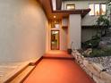Unique front entrance featuring an orange walkway, garden with Buddha statue, and glass door at 10592 Raven Run, Littleton, CO 80125