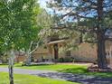 Beautiful home with brick accents, mature trees, and well-manicured lawn at 1095 Lake Woodmoor Dr, Monument, CO 80132