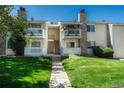 Close up of condo exterior featuring stone accents, private balconies, and lush lawn at 8555 Fairmount Dr # G103, Denver, CO 80247