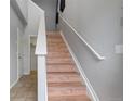 Light-filled stairway featuring wood steps, white risers and handrail, and neutral paint tones at 13000 W Grant Cir # C, Thornton, CO 80241