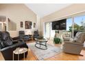 Spacious living room offers a vaulted ceiling, fireplace, balcony access, and wood floors at 929 Coneflower Dr, Golden, CO 80401