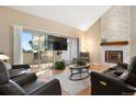 Comfortable living room featuring a stone fireplace, vaulted ceiling, leather seating, and access to a balcony at 929 Coneflower Dr, Golden, CO 80401