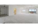 Expansive living room with white walls and light carpet, showcasing access to the kitchen and balcony at 7865 E Mississippi Ave # 1502, Denver, CO 80247