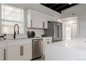 Modern white kitchen featuring stainless steel appliances, white cabinets, and a black ceiling at 7918 Raleigh Pl, Westminster, CO 80030