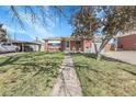 Well-maintained brick home featuring a spacious front yard, sidewalk, and convenient carport parking at 3022 Blackhawk St, Aurora, CO 80011