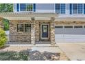 Inviting front porch with stone pillars leading to a navy blue front door with glass pane at 18807 E 51St Pl, Denver, CO 80249