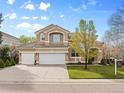 Elegant two-story home with a three-car garage, manicured lawn, and a tile roof at 9734 Tall Grass Cir, Lone Tree, CO 80124