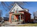 Classic brick home boasts a quaint front porch with seating and mature trees at 4403 Alcott St, Denver, CO 80211