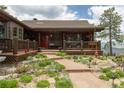 Charming log cabin exterior featuring a stone walkway, covered porch, and lush landscaping at 29095 Summit Ranch Dr, Golden, CO 80401