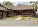 Charming log cabin with a red door, front porch, beautiful landscaping, and scenic surroundings at 29095 Summit Ranch Dr, Golden, CO 80401