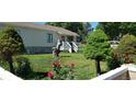 Charming front yard with lush green lawn, rose bushes, and well-placed trees, leading to a cozy home at 1940 E 95Th Ave, Thornton, CO 80229