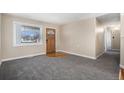 Inviting living room features plush gray carpet, fresh neutral paint, and a charming wood front door at 1940 E 95Th Ave, Thornton, CO 80229