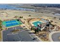 Aerial view highlighting community amenities including tennis courts, a pool, and a clubhouse by a serene lake at 6480 S Newcastle Way, Aurora, CO 80016