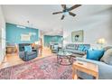 Inviting living room featuring a ceiling fan, blue accent wall and stylish furniture and a large area rug at 7193 S Versailles Way, Aurora, CO 80016