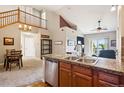 Open-concept view from kitchen with stainless appliances into the carpeted living room with fireplace at 8778 S Kipling Way # 304, Littleton, CO 80127