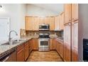 Bright kitchen features wood cabinets, granite counters, stainless steel appliances, and wood-look flooring at 8778 S Kipling Way # 304, Littleton, CO 80127