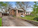 Charming brick home with covered front porch and long driveway, surrounded by mature trees and lush greenery at 2731 S Logan St, Englewood, CO 80113