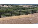 Scenic backyard view with a wooden fence, hillside scenery, and distant residential neighborhood at 4316 Ridgewalk Pt, Arvada, CO 80007