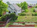 Charming home showcasing a lush yard with raised garden beds and a stairway to the front door at 2809 Yates St, Denver, CO 80212