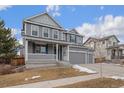 Two-story house with gray siding, a large front porch, and a two-car garage at 12243 Joplin St, Commerce City, CO 80603