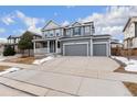 Two-story house with gray siding, a large front porch, and a two-car garage at 12243 Joplin St, Commerce City, CO 80603