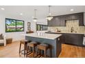 Modern kitchen with center island, hardwood floors, custom cabinetry, and stainless steel appliances at 4634 W Tufts Cir, Denver, CO 80236