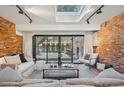 Bright living room featuring exposed brick walls, a skylight, and sliding doors to the outside patio at 4634 W Tufts Cir, Denver, CO 80236