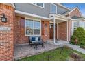 Inviting front porch with brick, quaint seating, and view of the home's architectural details at 762 Hughes Ln, Highlands Ranch, CO 80126