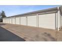 Row of garage spaces with white doors and a paved driveway at 750 S Clinton St # 6B, Denver, CO 80247