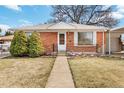 Close-up of a brick home with a small garden, black railings, and a welcoming front door at 6900 Avrum Dr, Denver, CO 80221