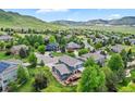 Aerial view of a neighborhood with lush green yards and mature trees, with mountain views in the distance at 18967 W 54Th Ln, Golden, CO 80403