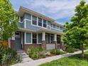 Inviting home exterior with a covered porch, brick accents, and lush greenery surrounding the walkway at 5445 Verbena St, Denver, CO 80238