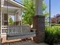 Inviting front porch with swing and brick column detail, offering a relaxing outdoor space at 5445 Verbena St, Denver, CO 80238